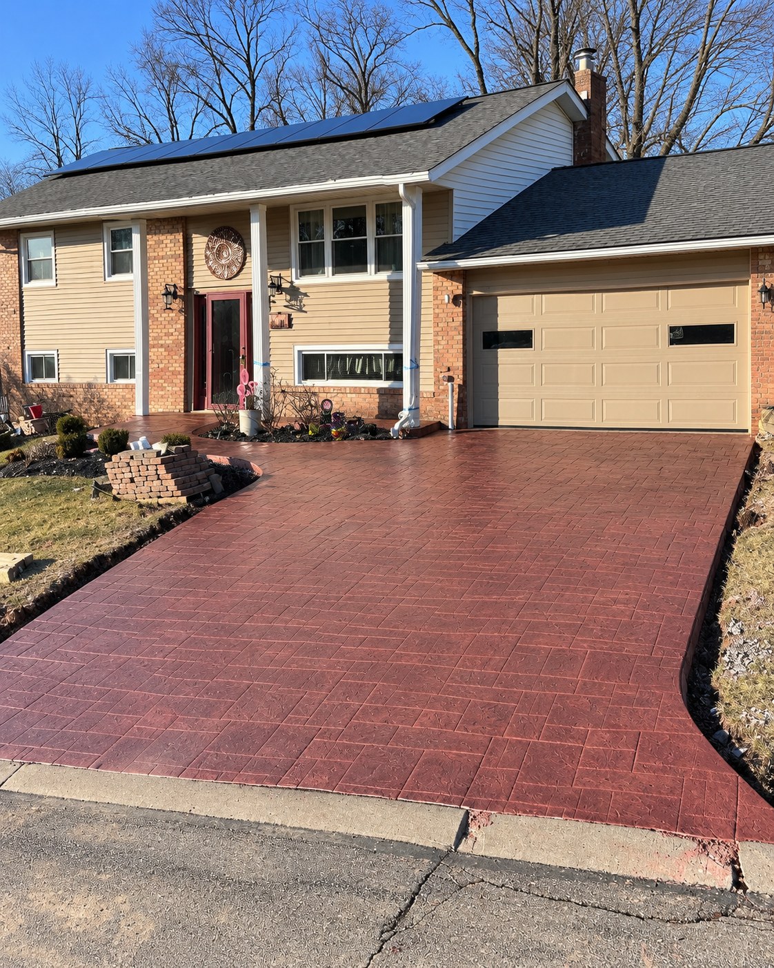 Red stamped concrete driveway in front of a split-level home